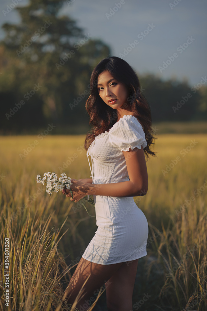 Lifestyle fashion portrait of stylish young asian woman wearing beige outfit posing at the rice field