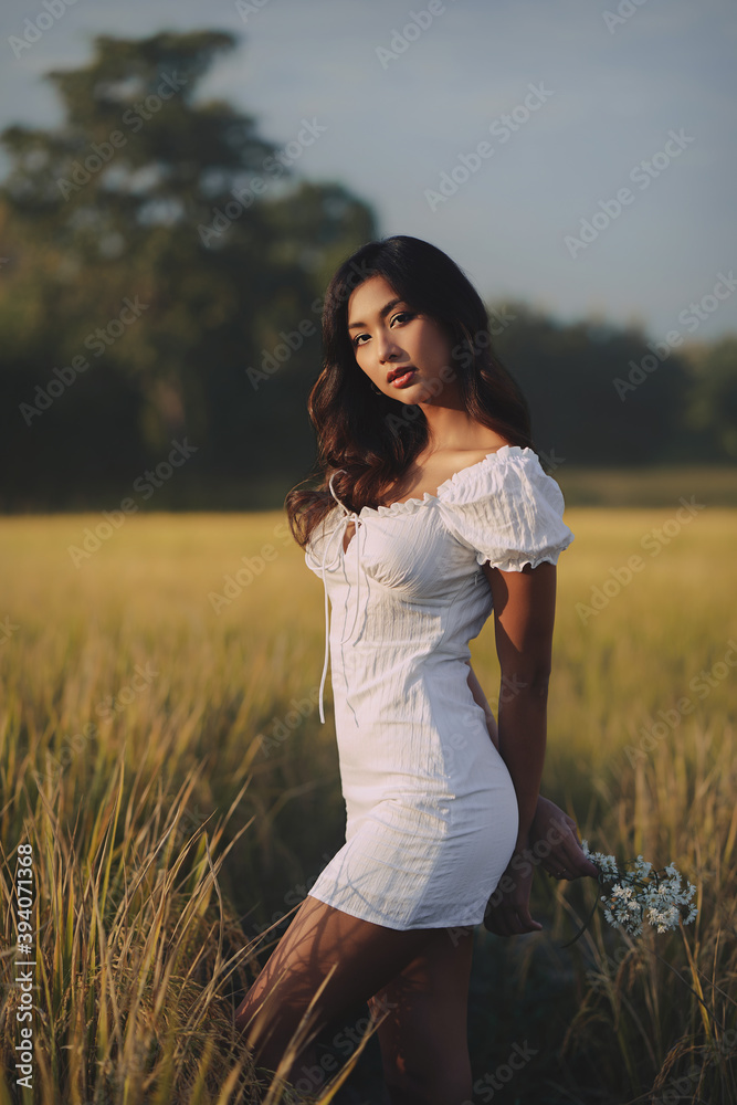 Lifestyle fashion portrait of stylish young asian woman wearing beige outfit posing at the rice field
