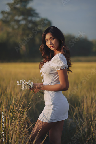 Obraz na płótnie Lifestyle fashion portrait of stylish young asian woman wearing beige outfit posing at the rice field w salonie