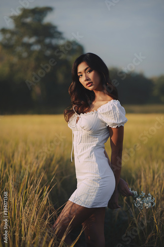 Obraz na płótnie Lifestyle fashion portrait of stylish young asian woman wearing beige outfit posing at the rice field w salonie