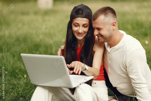 Couple in a spring city. Lady with a laptop. People sitting on a grass.