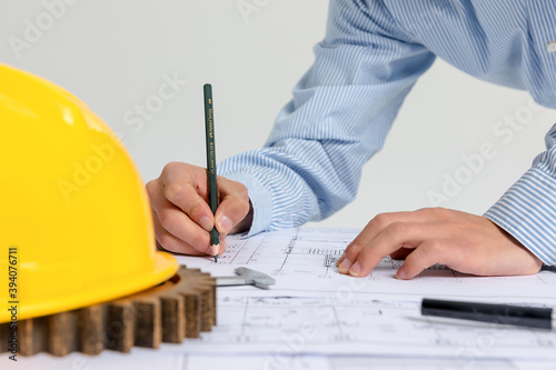 Hand over construction plans with yellow helmet. laptop and drawing tool