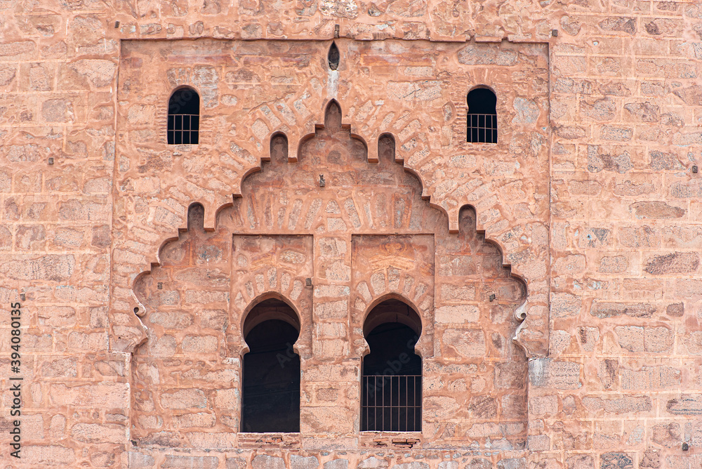 Ancient walls of medina in Marrakech, part of Kutubiyya mosque, arabian style of doors and windows, buildings by red clay, Morocco