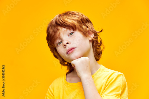 Red hair child holds hand near face some close-up yellow 