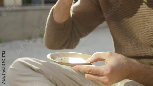 Close up male hands holding cup of coffee. Summer, sunny day