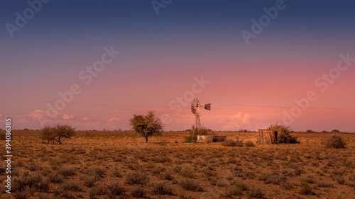 Windmill in a breathtaking landscape at sunset in the Kalahari desert of Namibia.