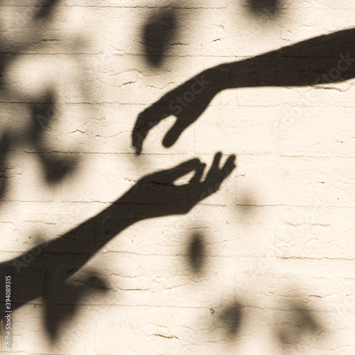shadow on the wall of hands of two persons nearly touching longing for contact