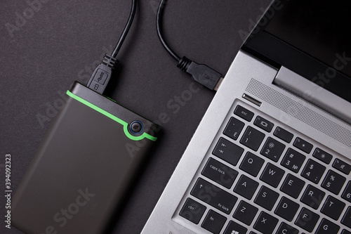 Hard disk and laptop on a black table close-up. photo