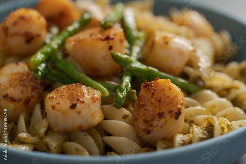Fusilli pasta with scallops and asparagus in blue bowl closeup