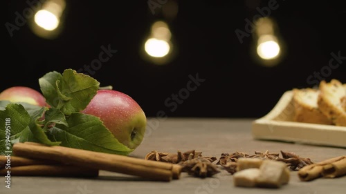 Closeup fresh apples with leaves and spices on the table. Blurry lights on black background. Healthy eating. Close up, camera slowly moving on the slider, dolly shot