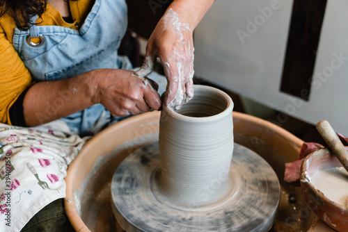 Potter making ceramic pot on the pottery wheel with hands