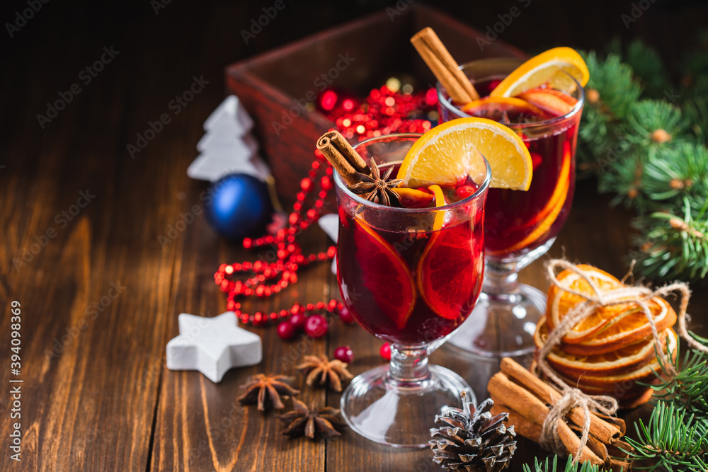 Hot Christmas drink of wine, fragrant spices and fruits in a glass on a wooden rustic background with Christmas decorations. Holiday hot mulled wine or punch.