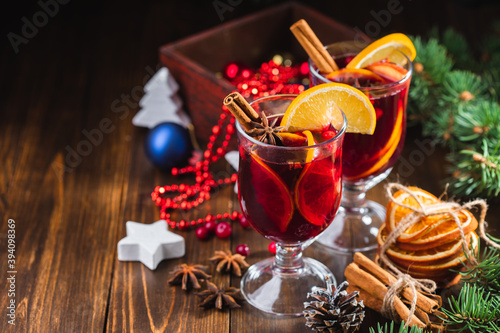 Hot Christmas drink of wine  fragrant spices and fruits in a glass on a wooden rustic background with Christmas decorations. Holiday hot mulled wine or punch.