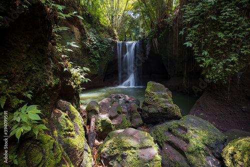 Waterfall landscape. Beautiful hidden waterfall in tropical rainforest. Foreground with big stones. Slow shutter speed  motion photography. Suwat waterfall  Bali  Indonesia