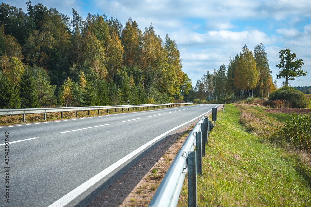 View of the highway road in the fall. Traveling background. Asphalt highway passing through the forest. Latvia. Baltic.