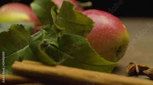Macro shot fresh apples with leaves and spices on the table on black background. Healthy eating. Camera slowly moving on the slider, dolly shot