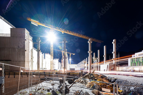 Floodlit tower crane on building construction site at night