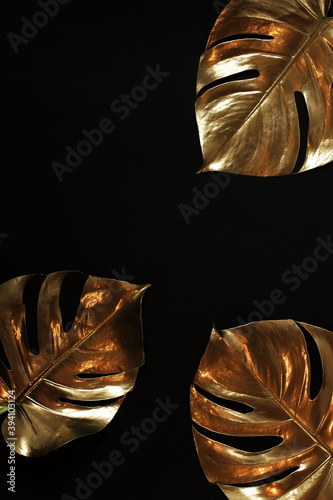 Gold monstera leaves frame close up isolated on a black background  top view.  abstract poster.