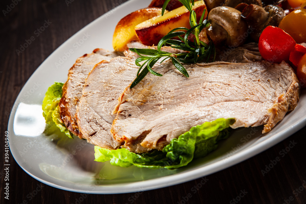 Roasted pork ham, champignons and fried potatoes on wooden table