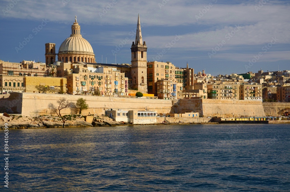 Architecture in the Maltese capital Valletta. Stone houses, multicolored balconies, church dome, sunny day.