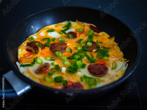 Breakfast - scrambled eggs with sausages and vegetables in frying pan
