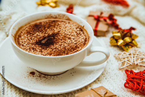 Coffee on the background of a warm knitted blanket with gifts and holiday bows.Hot winter drink.