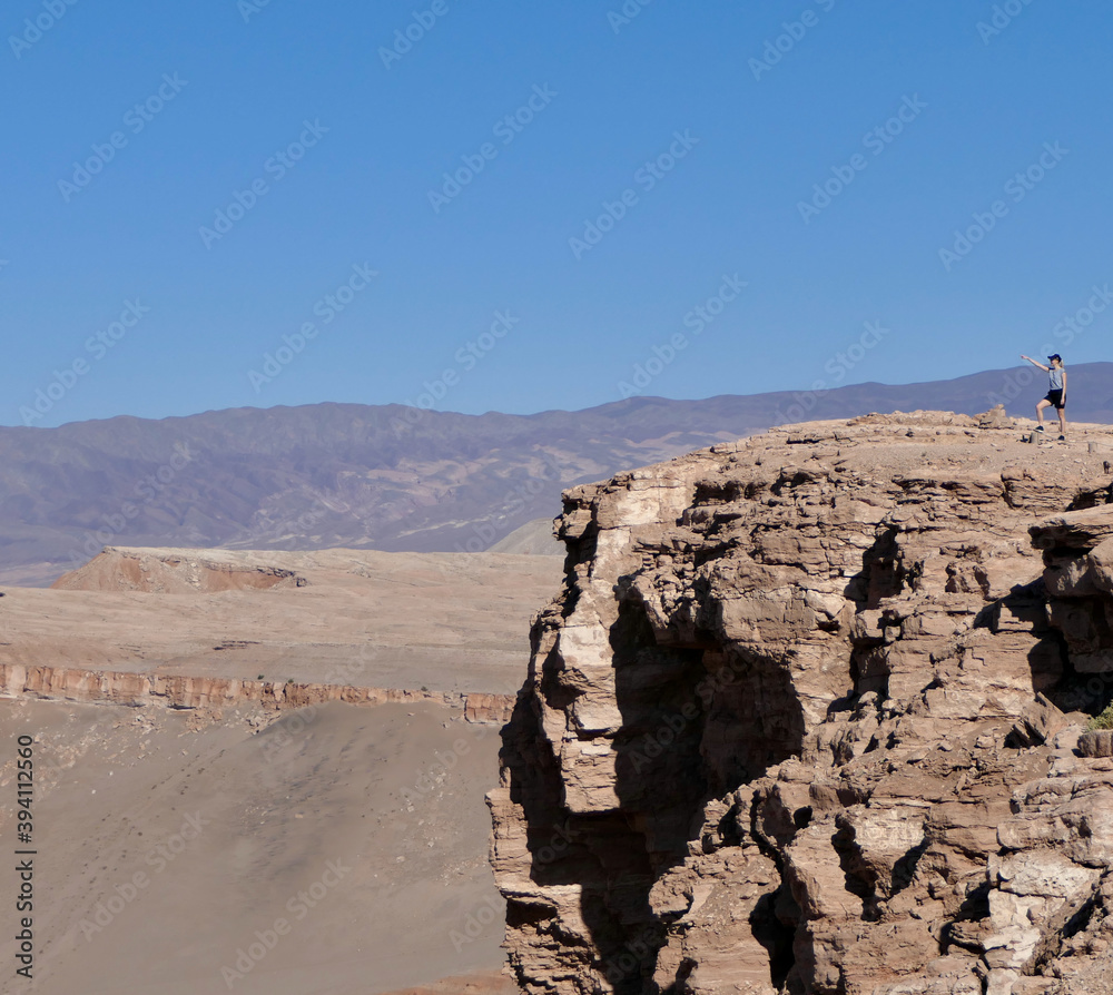 Stone cliff in Atacama salt desert landscape with blond tourist, Chile