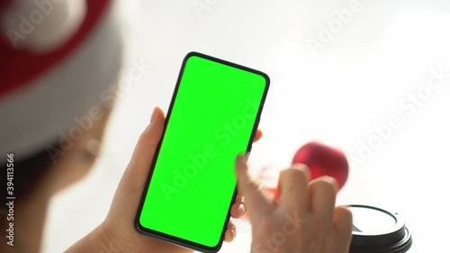 Close-up shot of green screen template smartphone in female hands at home offise. The template can be used to advertise purchases on Christmas Eve. Modent technology and information concept. POV photo