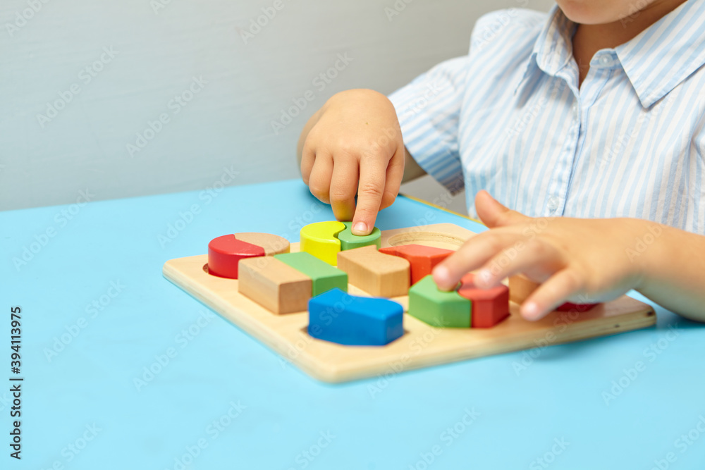The child collects a sorter. Educational logic toys for kid's. Children's hands close-up. Montessori Games for Child Development. Multicolored logic sorter on white background. The child collects a sorter. Educational logic toys for kid's. Children's hands close-up. Montessori Games for Child Development. Multicolored logic sorter on white background.