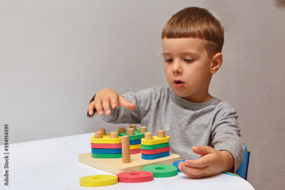 The boy is playing in his room. Learning shapes and colors. A child plays with a sorter. Educational logic toys for kid's. Montessori Games for Child Development. The boy is playing in his room. Learning shapes and colors. A child plays with a sorter. Educational logic toys for kid's. Montessori Games for Child Development.