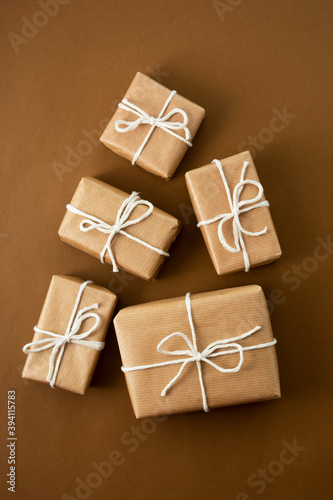 Christmas gift boxes wrapped with brown kraft paper over brown background. Top view.