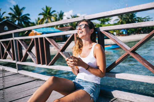 Adult woman using smartphone and laughing on pier