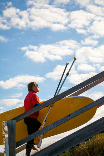 Surfer carrying a Paddle-board from the beach photo