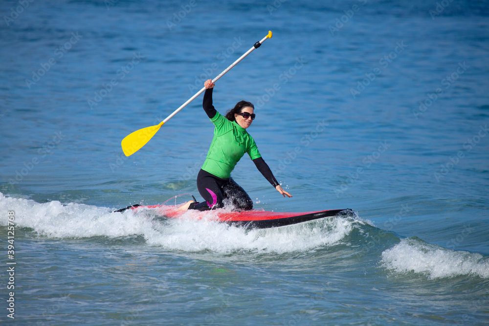 Middle aged woman on paddle board in ocean Middle aged woman on paddle board in ocean