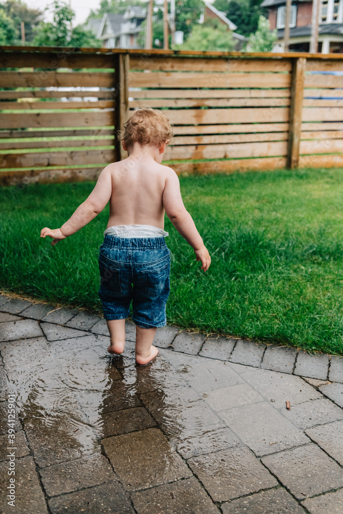 Toddler splashing in summer rain puddle Toddler splashing in summer rain puddle