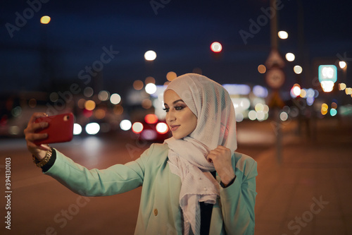 Young muslim women taking photos on the street. photo