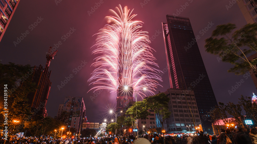 Fototapeta premium Taipei City Night landscape and Taipei 101 skyscraper is lit up by fireworks. People watching and taking photos and videos around buildings to celebrate the new year event.