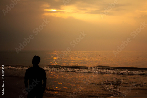 silhouette of a person walking on the beach at sunset