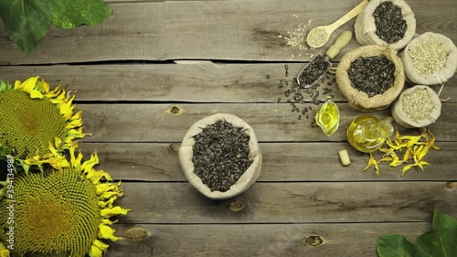 Sunflower oil and seeds on an old wooden table. Top view. The man's hands put a bag of sunflower seeds on the table.