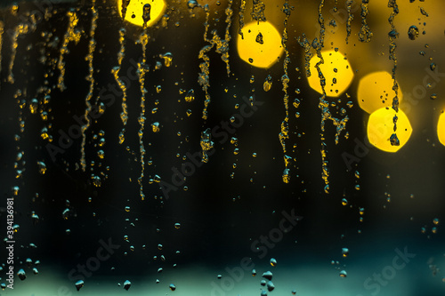 abstract background, streams of rain and snow on the glass on the background of street lighting