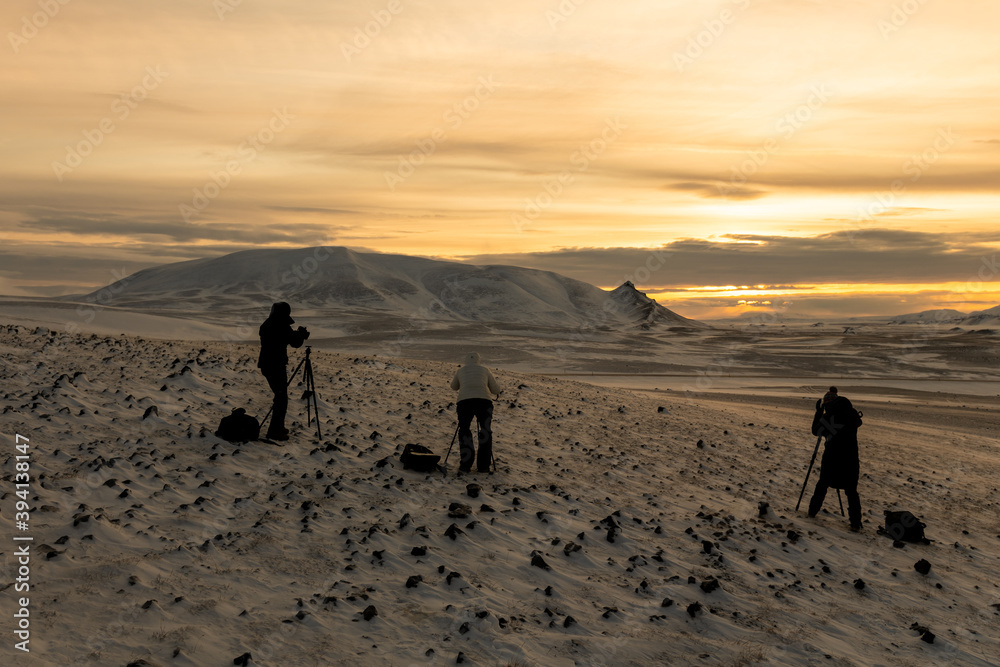 Group of landscape photographers making photos of cloudy sunset in winter Iceland