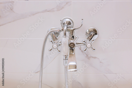 Assemble water tap, bathroom faucet mounted on a white wall in a bathroom