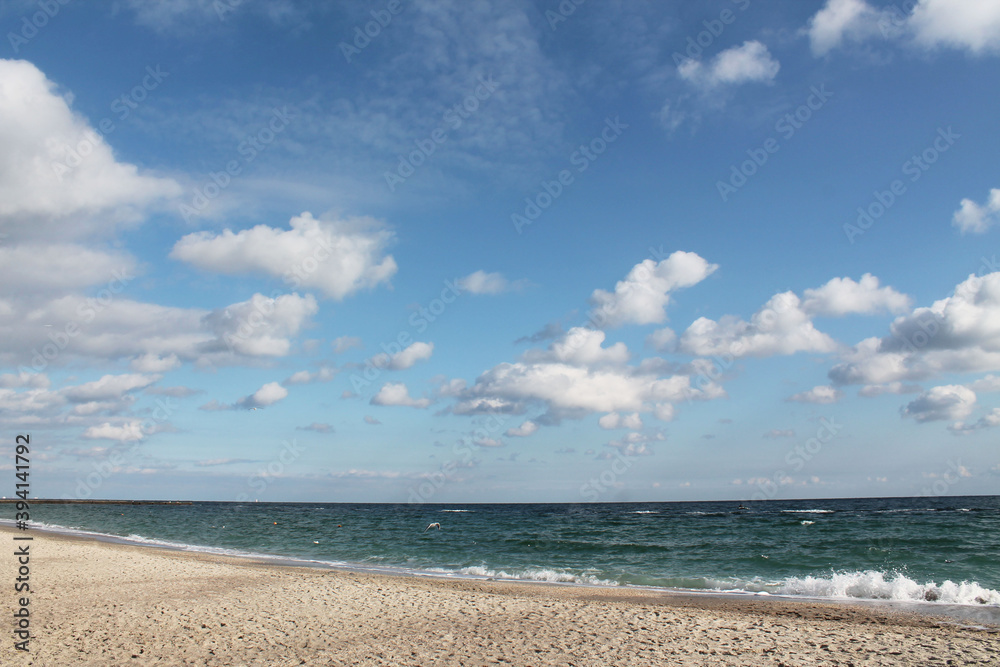 Marine autumn landscape. Sandy coast, turquoise sea with small waves and blue cloudy sky. Marine autumn landscape. Sandy coast, turquoise sea with small waves and blue cloudy sky.