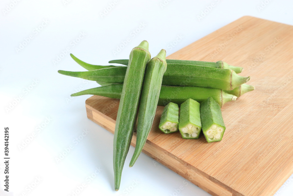Fresh vegetable okra on wooden tray on white background