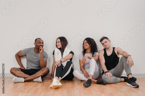 Portrait of four happy multinational friends siting on floor in gym after training © Denys Kurbatov
