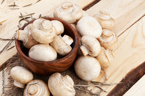 Champignon mushrooms in bowl on wooden background