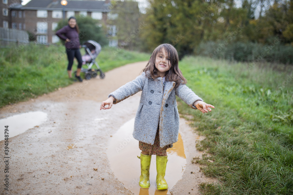 Obraz premium Happy little girl smiling adorably after jumping in a muddy puddle