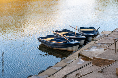 Three blue and white rowing boats moored on a tranquil river on a sunny day