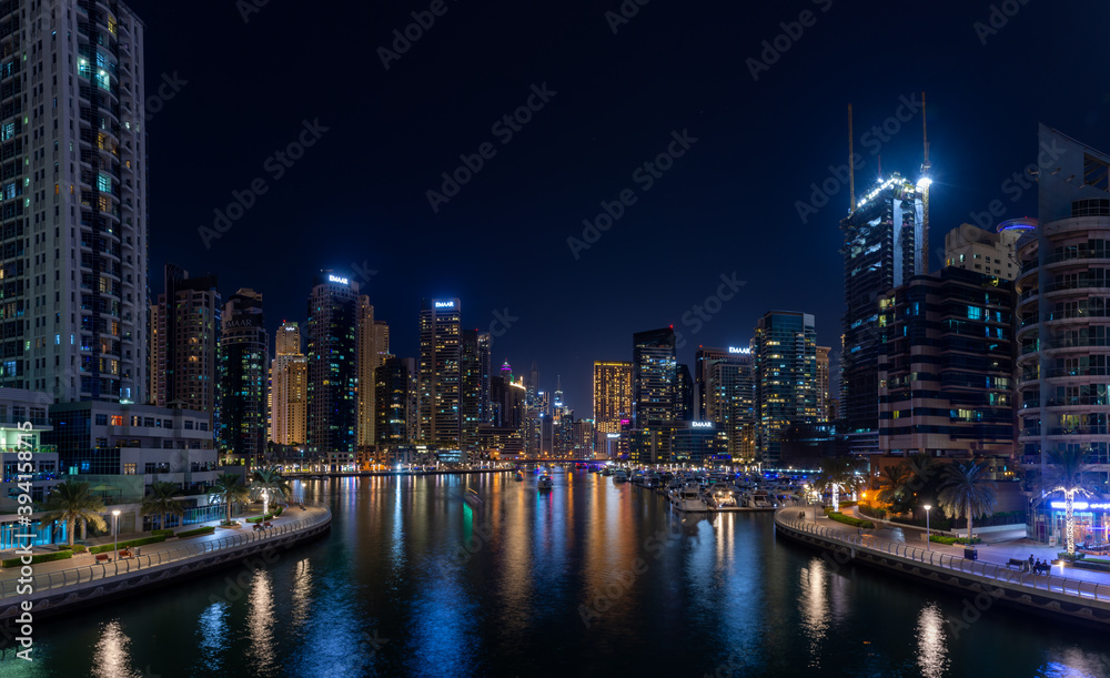 Obraz premium Dubai Marina Yacht Club long exposure panorama at night with lights of skyline and creek for luxury vacation and travel