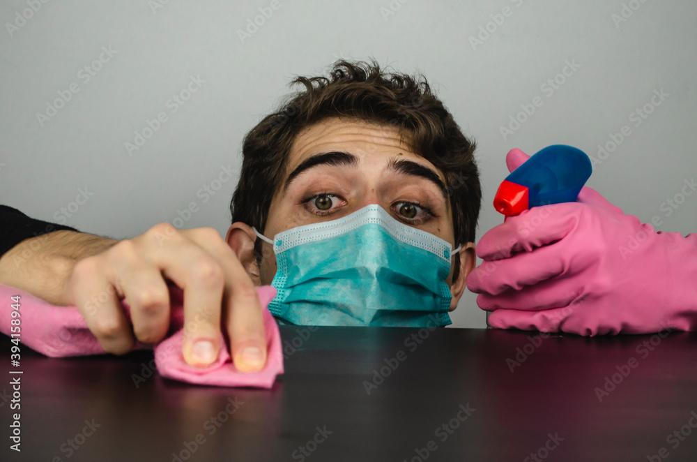 hombre joven con mascarilla guantes y desinfectante limpiando - obrazy, fototapety, plakaty 